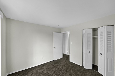 a bedroom with white walls and white closet doors